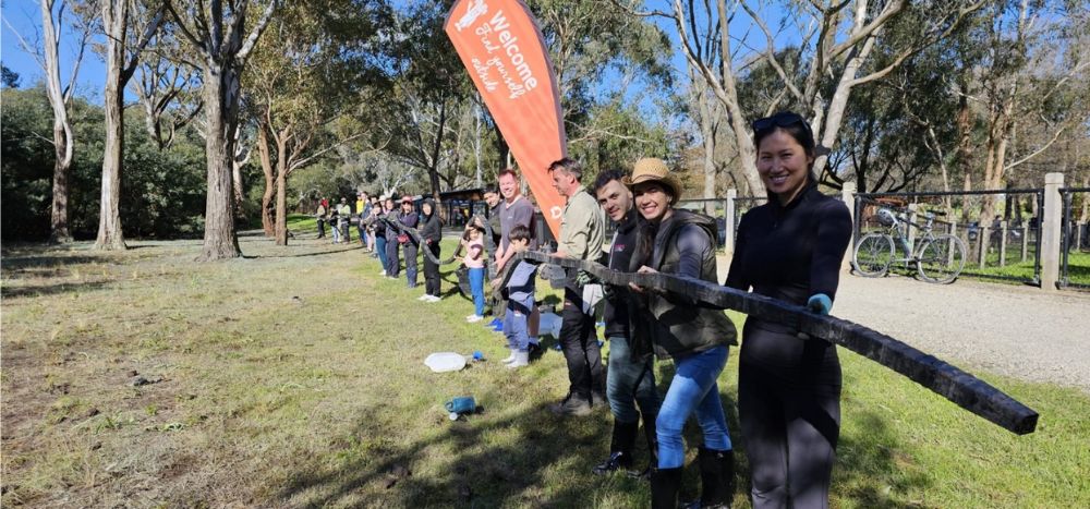 Group of people in a line under orange sign reading 'Welcome. Find yourself outside